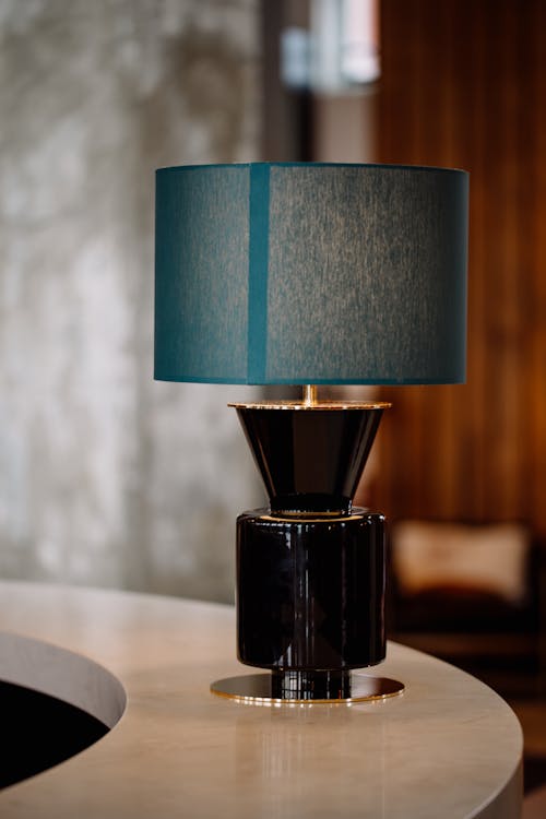 A black and gold table lamp with a blue shade