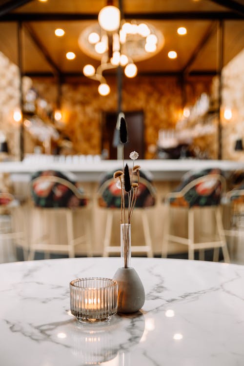 A candle sits on a marble table in front of a bar