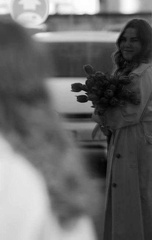 A woman in a trench coat holding flowers