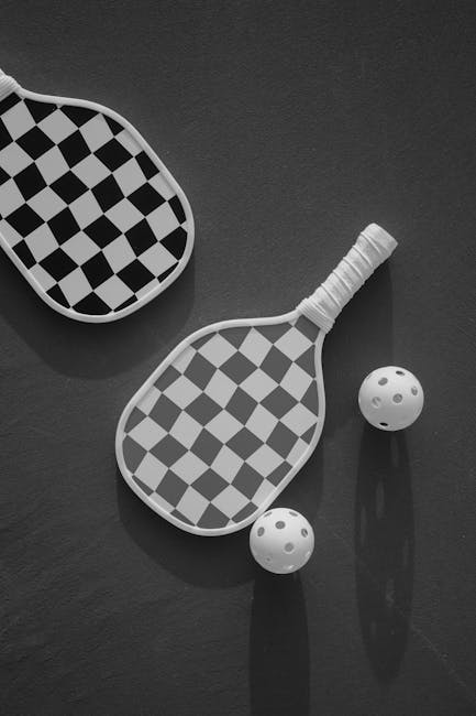 Stylish checkered paddles and balls on a dark surface, top view.