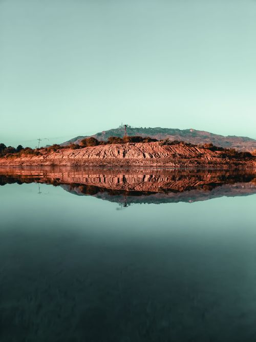 Free Serene lake reflecting rocky terrain and hills at Mount Abu, India. Perfect symmetry and tranquility. Stock Photo