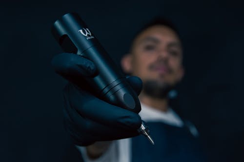 A man in black gloves holding a black pen