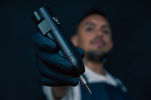 A man in black gloves holding a black pen