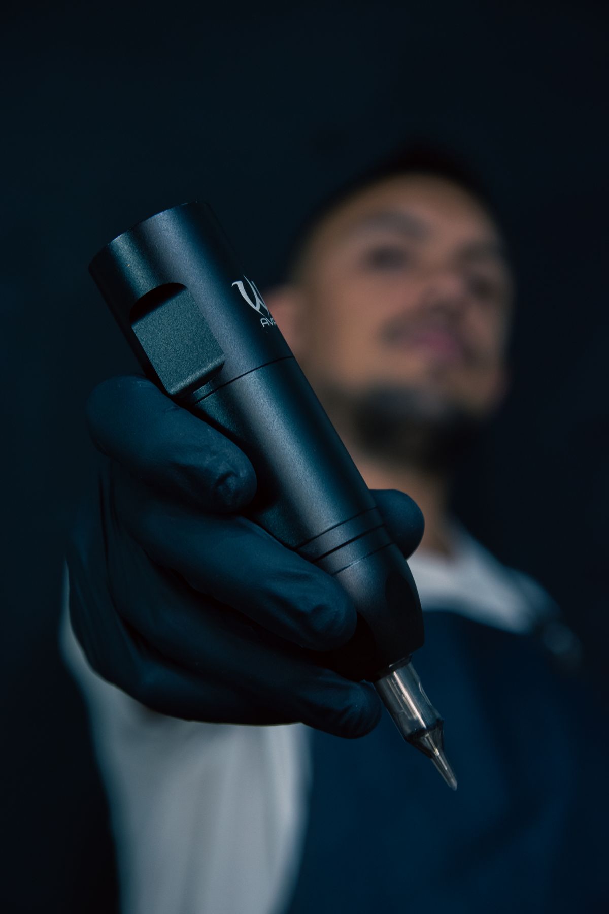Tatuador profesional trabajando con máquina de tatuaje y guantes