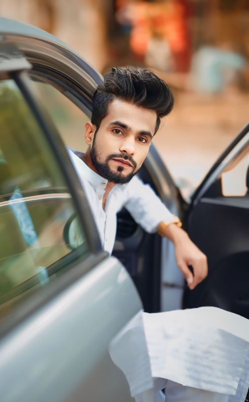 Free Fashionable man with black hair and beard in a car doorway, highlighting modern style. Stock Photo