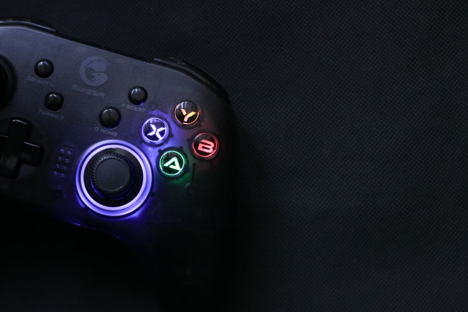 Close-up of a glowing gaming controller against a dark background, highlighting technology and entertainment.