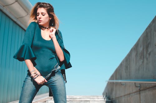 Photo of Woman in Green Bodysuit and Blue Denim Jeans Posing