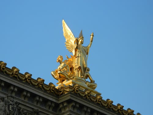 Gold statue on top of a building with a golden angel