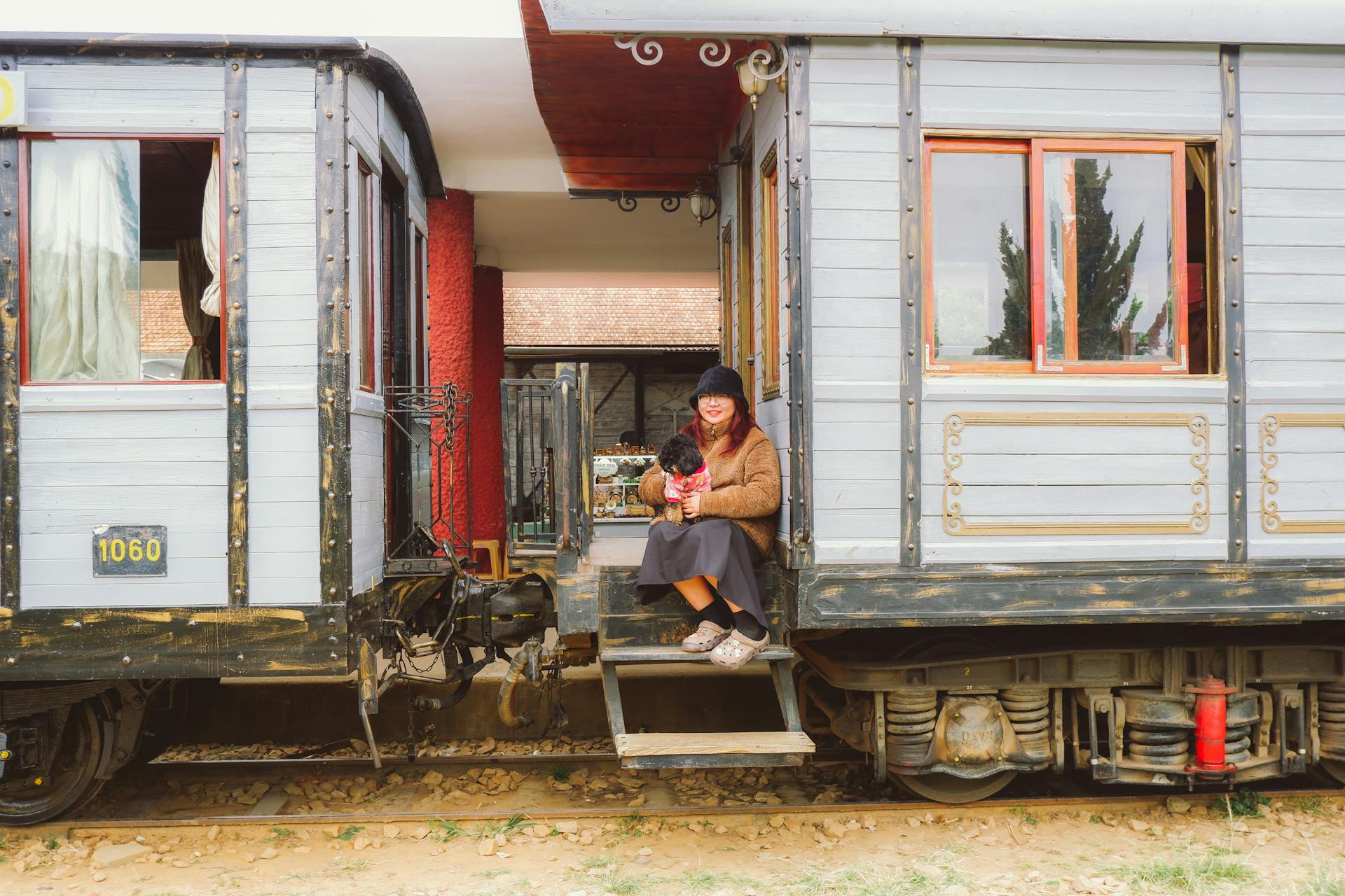 Tourist with a Dog Sitting Between the Vintage Train Cars