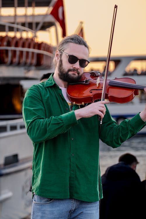 A man in sunglasses playing the violin on a boat