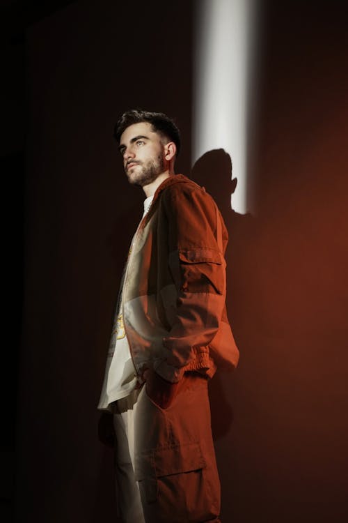A man in an orange jacket standing in front of a light