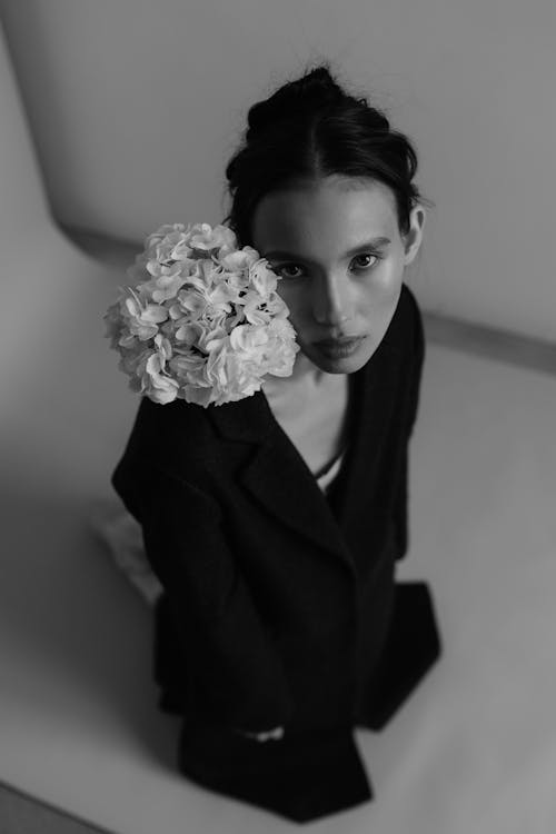 A woman in a black suit holding a flower