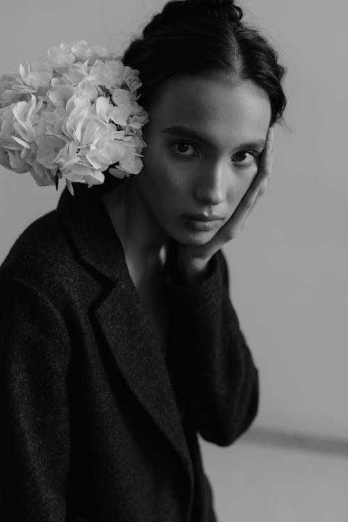 A woman with flowers in her hair posing for a black and white photo