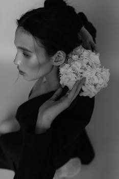 Stylish black and white portrait of a woman holding a bouquet, evoking elegance and sophistication.
