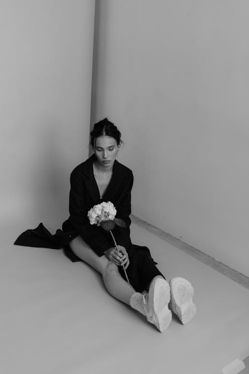 A woman sitting on the floor with a flower