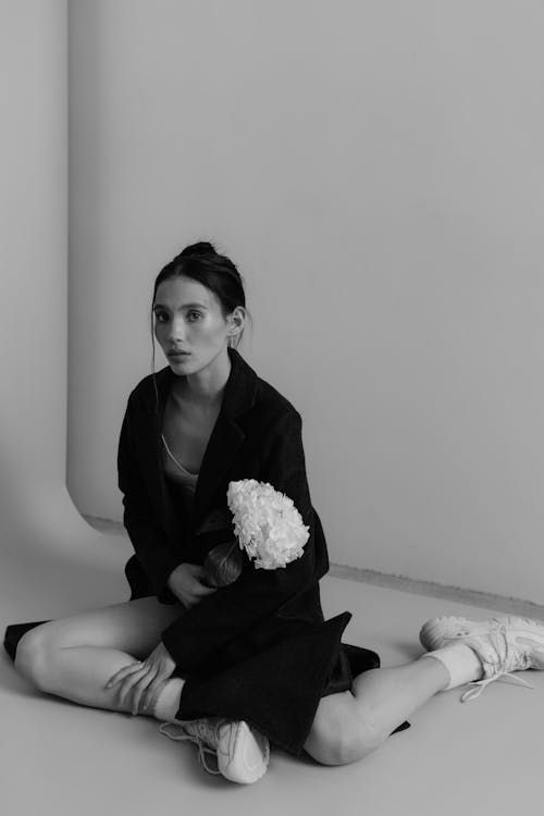 A woman sitting on the floor with a flower