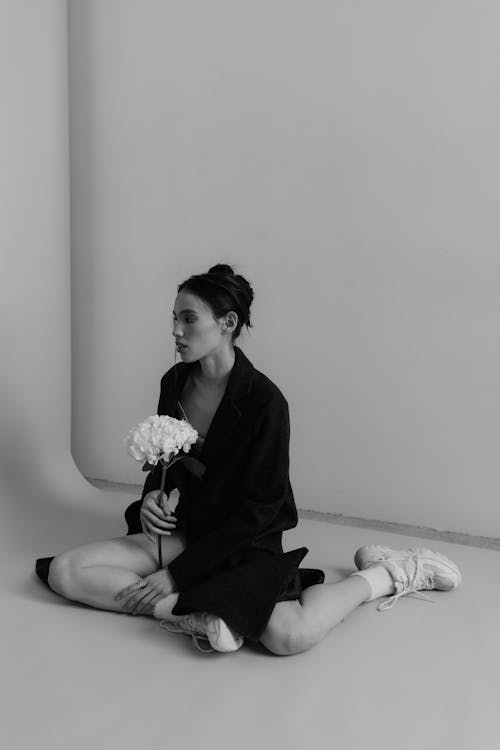 A woman sitting on the floor with a flower