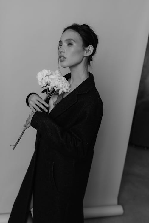 A woman in a black coat holding flowers
