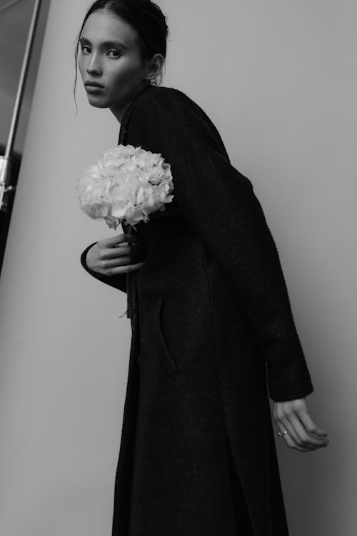 A woman in a coat holding flowers