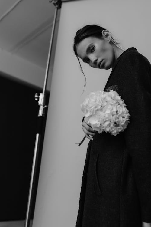 A woman in a black coat holding a bouquet