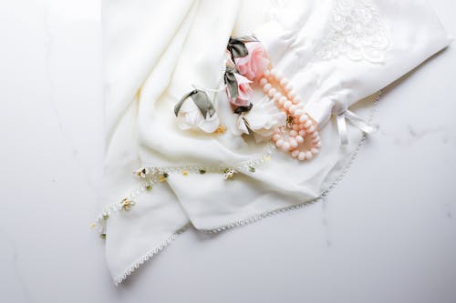 A white silk scarf with pearls and flowers
