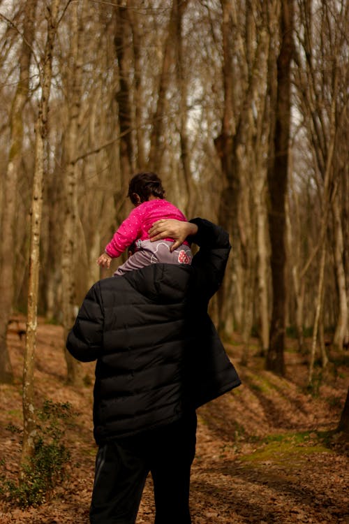 A man carrying a little girl in the woods