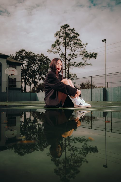 A woman sitting on a tennis court with a reflection