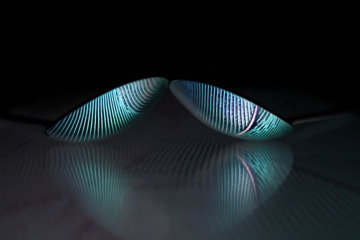 Abstract image of two reflective spoons with striped patterns set against a black background.