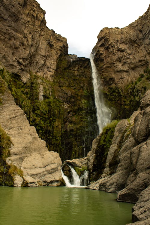 A waterfall is seen in the middle of a canyon