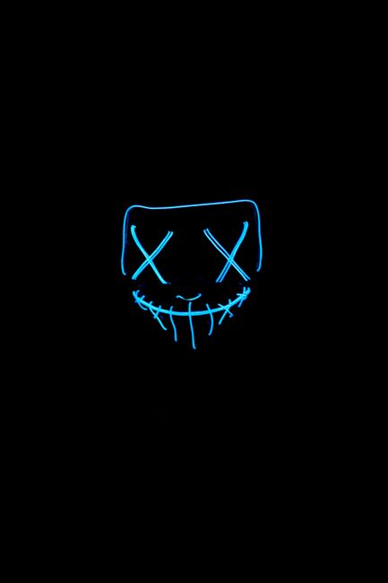 A fluorescent mask glows in the dark, creating a spooky aura.