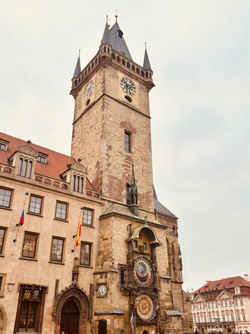 A clock tower in a city square with people walking by