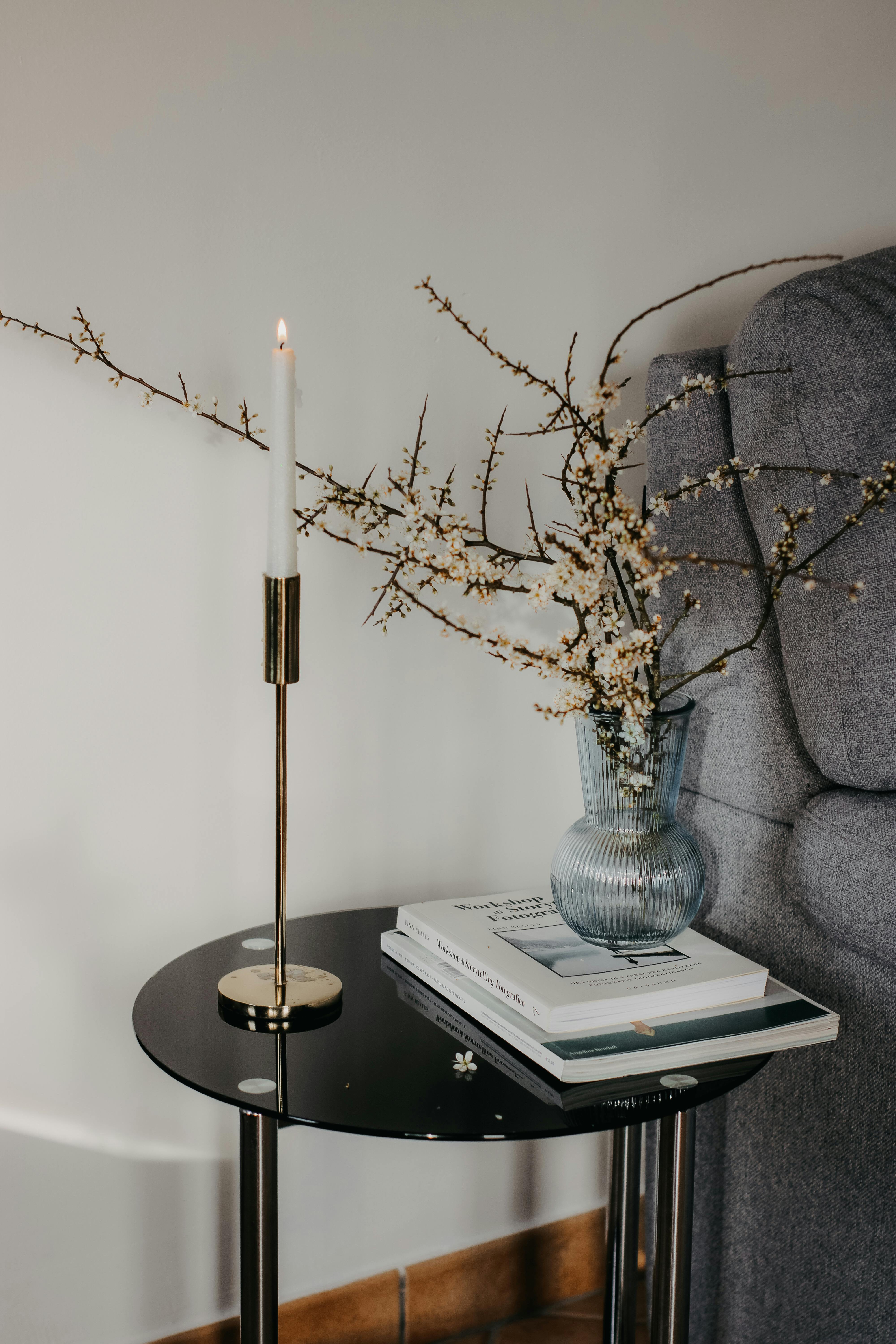 Stylish living room setup with a candle, books, and flowers in a vase on a table.