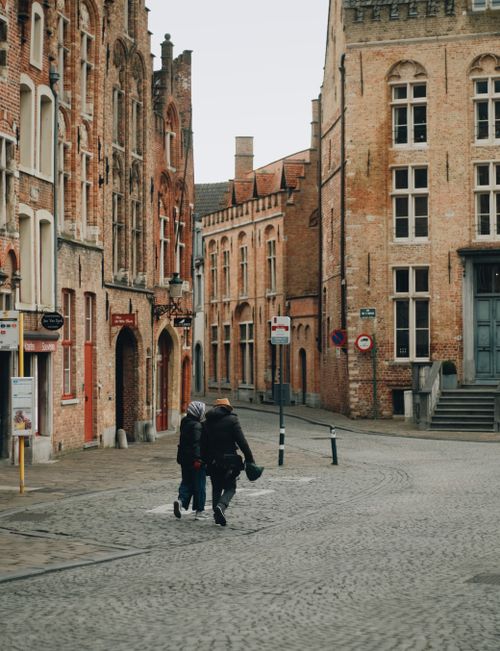 Free A picturesque view of a cobblestone street with historic buildings and pedestrians in an old town setting. Stock Photo