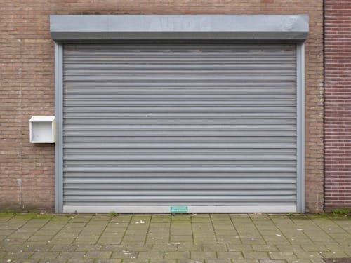 A grey metal roller door with a green door