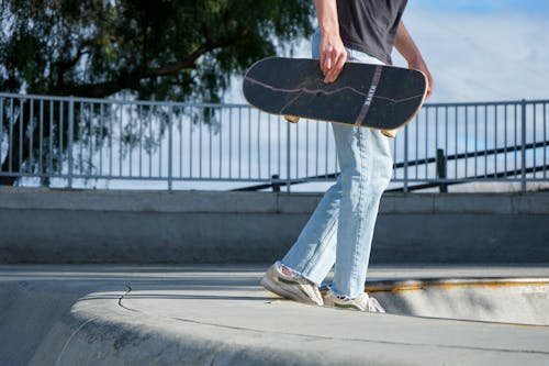 A person holding a skateboard at a skate park