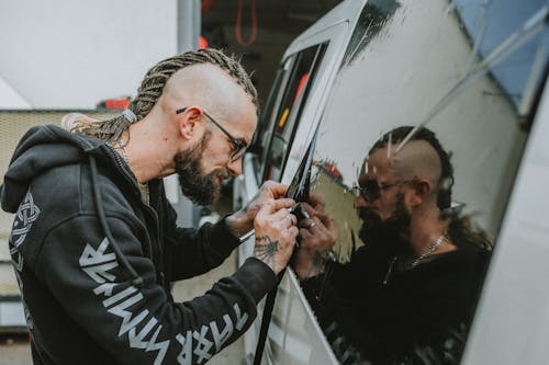 A man with dreadlocks is fixing the side of a van