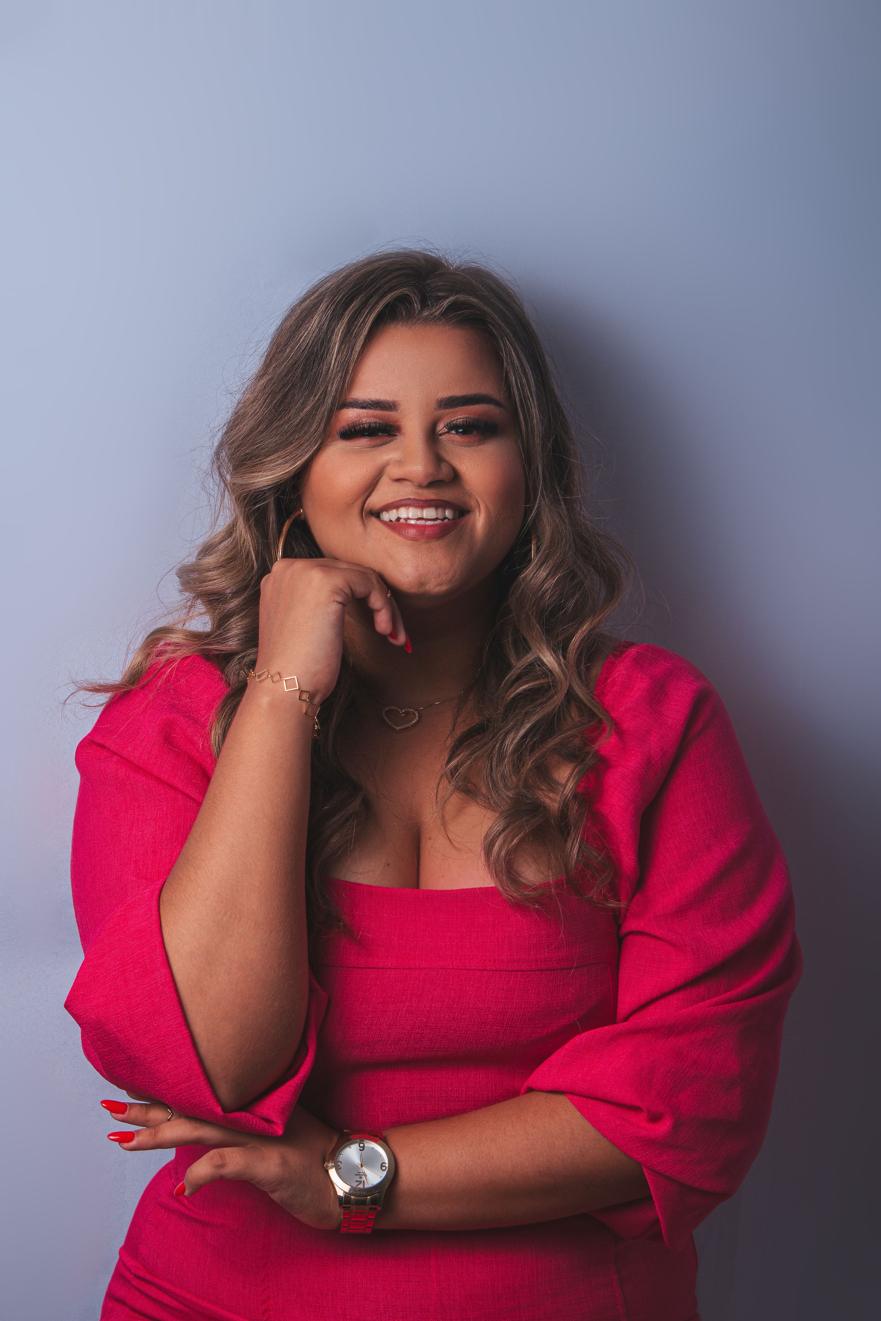 Smiling woman posing confidently in a pink dress during a studio photoshoot.