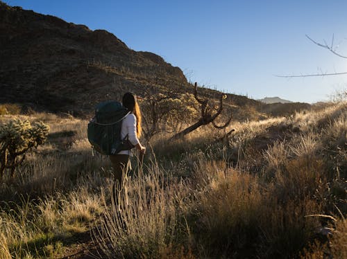 A woman with a backpack walks through a desert
