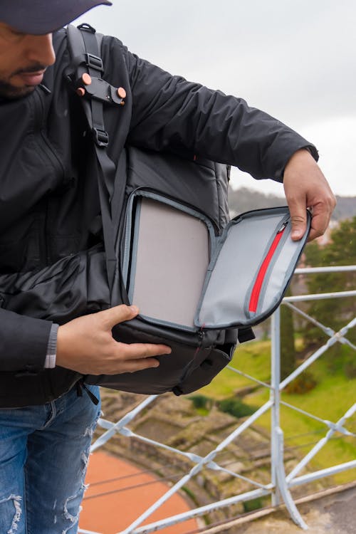 A man holding a laptop case on a bridge