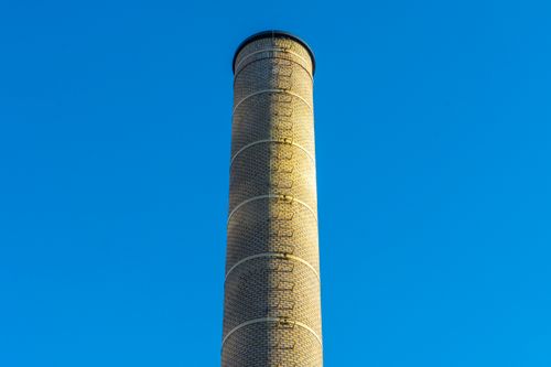 Free Tall industrial chimney under a clear blue sky in Den Haag, Netherlands. Stock Photo