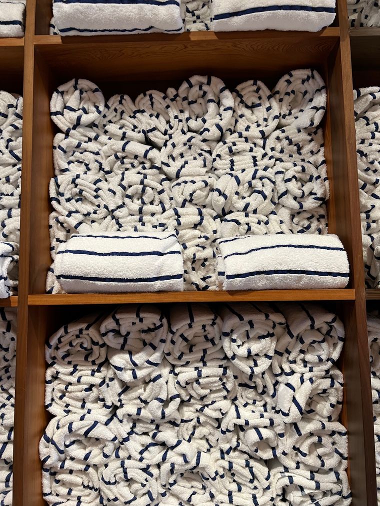Folded striped towels stacked on an oak bathroom shelf. Photo by Lauren Cuddy on Pexels