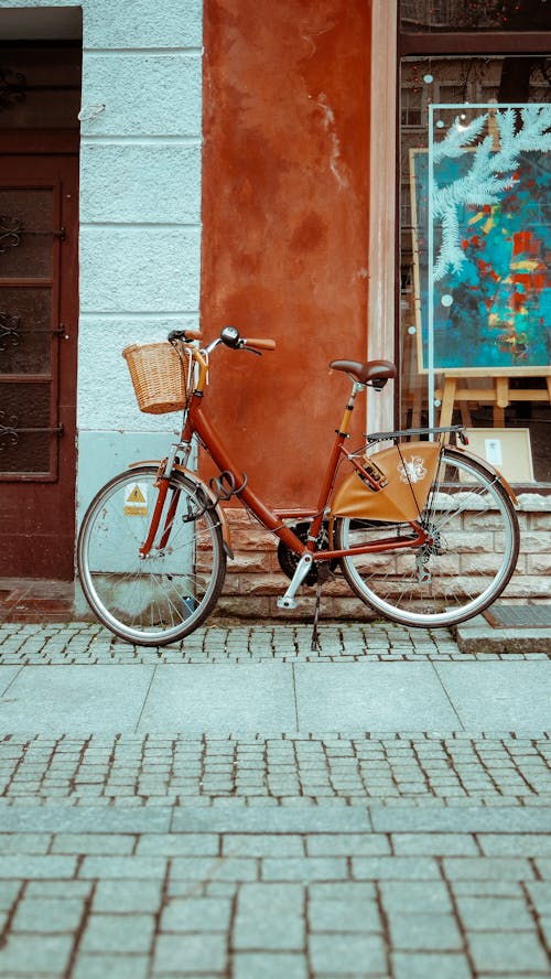 A bicycle parked against a wall with a basket