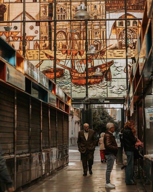 People walking through an alleyway with stained glass windows