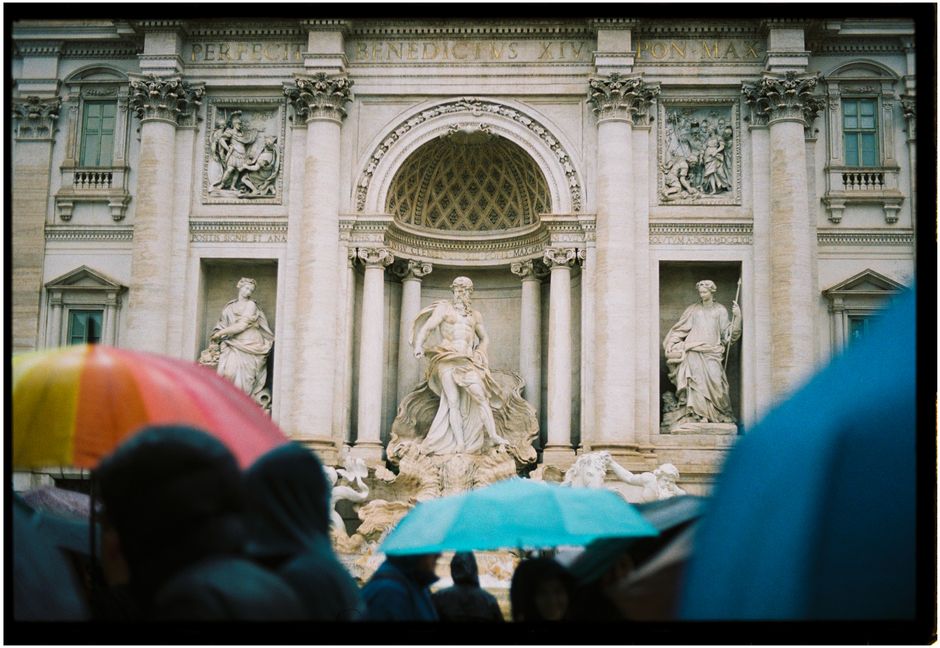 Trevi Fountain in Rome on a rainy day with vibrant umbrellas in the foreground.