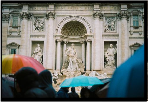 Free Trevi Fountain in Rome on a rainy day with vibrant umbrellas in the foreground. Stock Photo