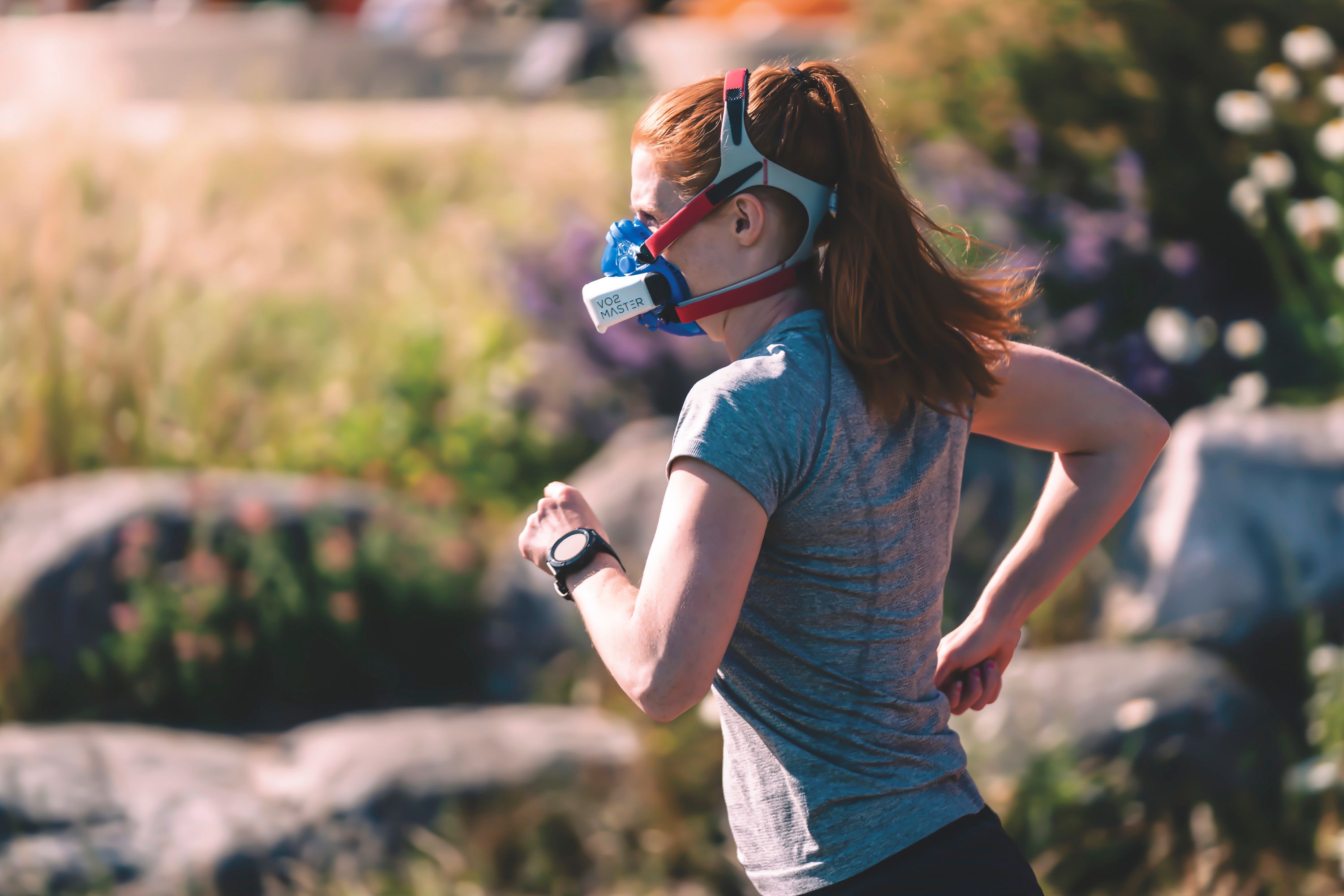 Woman in face mask jogging outdoors, showcasing sports and safety in an outdoor environment.