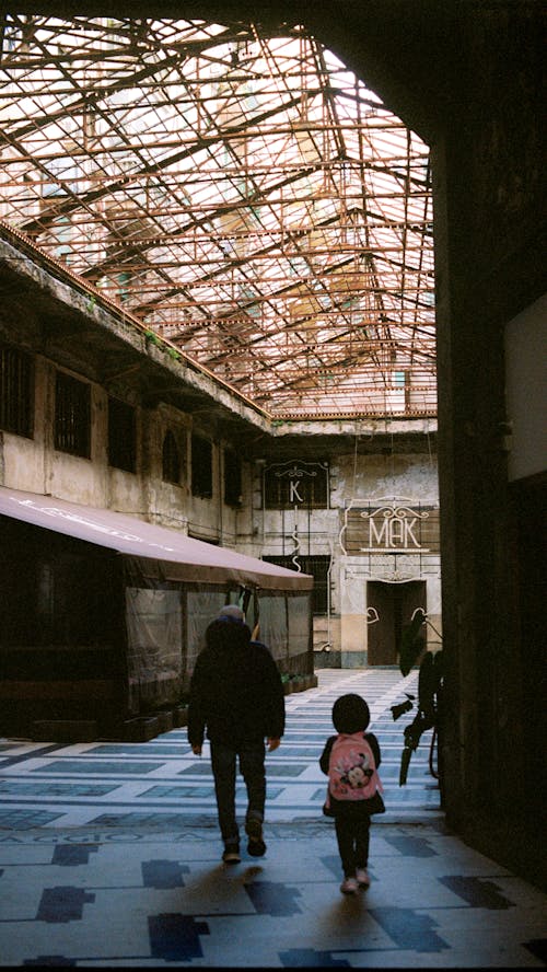 A man and a child walk through an abandoned building