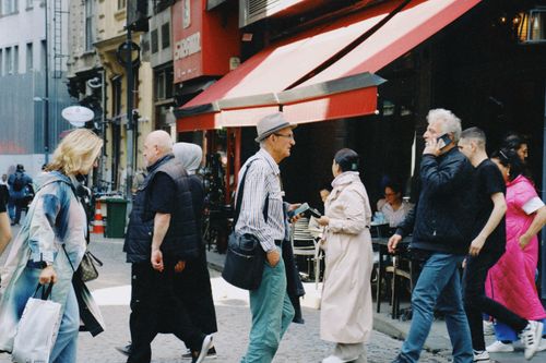 Free Urban street with diverse people walking past cafes and shops. Stock Photo