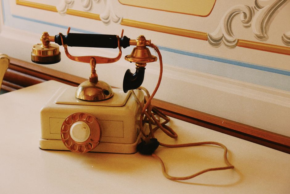 A classic vintage rotary phone with ornate details on a decorative table, conveying retro charm.