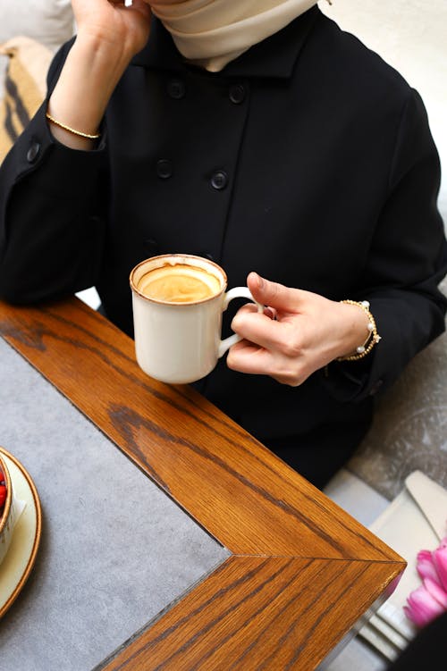 A woman in a hijab holding a cup of coffee